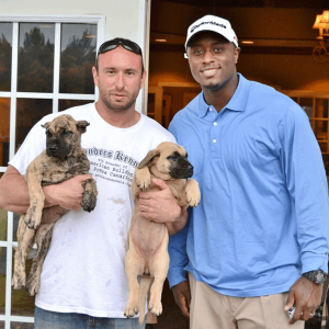 DJ Shockley with a Sanders Kennels employee holding 2 Presa Canario puppies