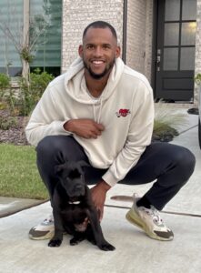 Man posing on the sidewalk with a black Presa Canario