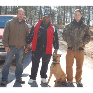 3 men posing with a beige adult Presa Canario